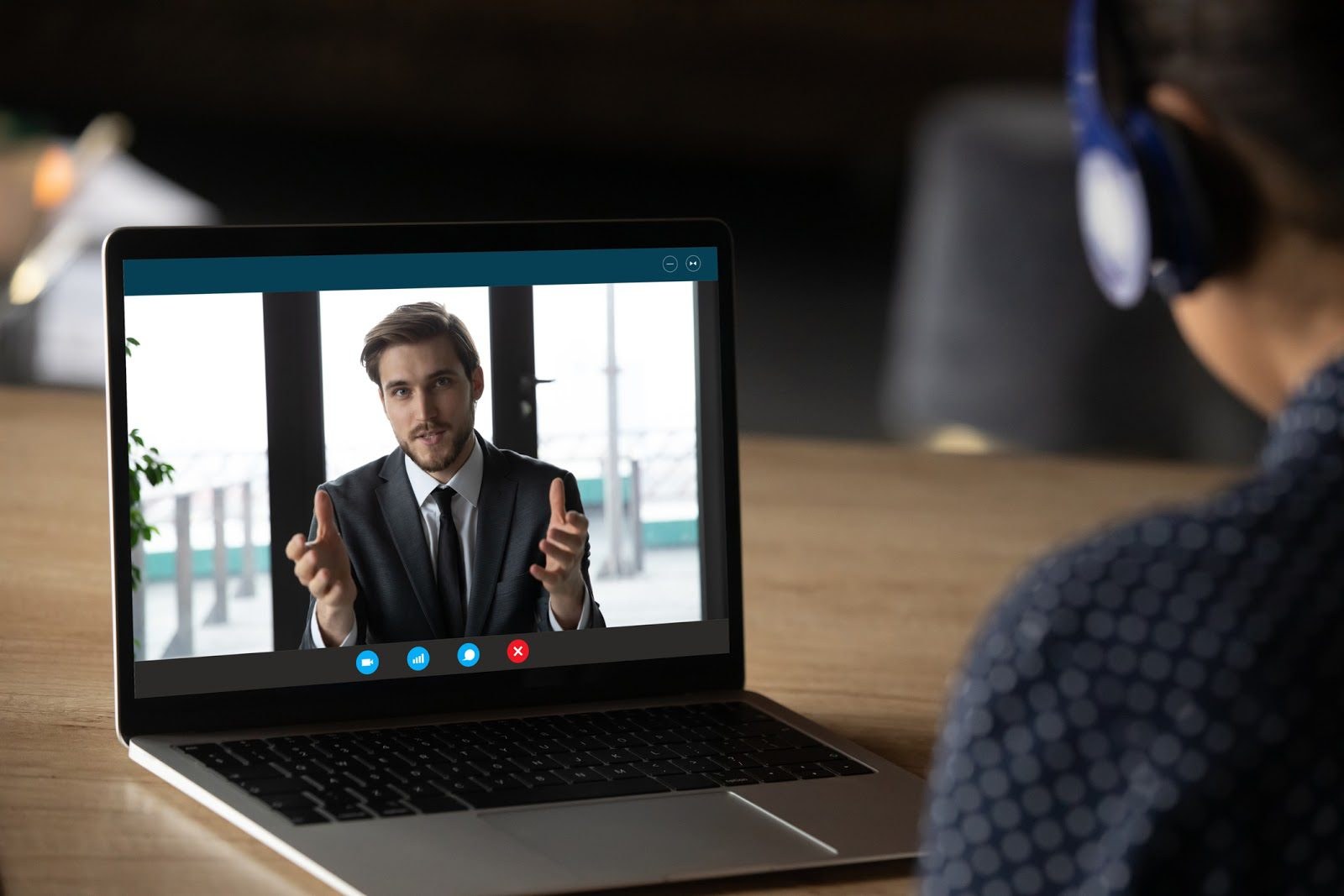 Over-the-shoulder view of a laptop showing a virtual meeting with a financial advisor