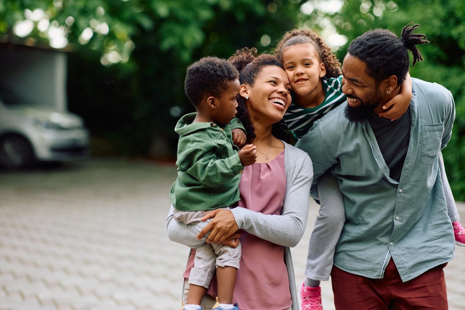 A joyful family of four laughing and embracing outdoors